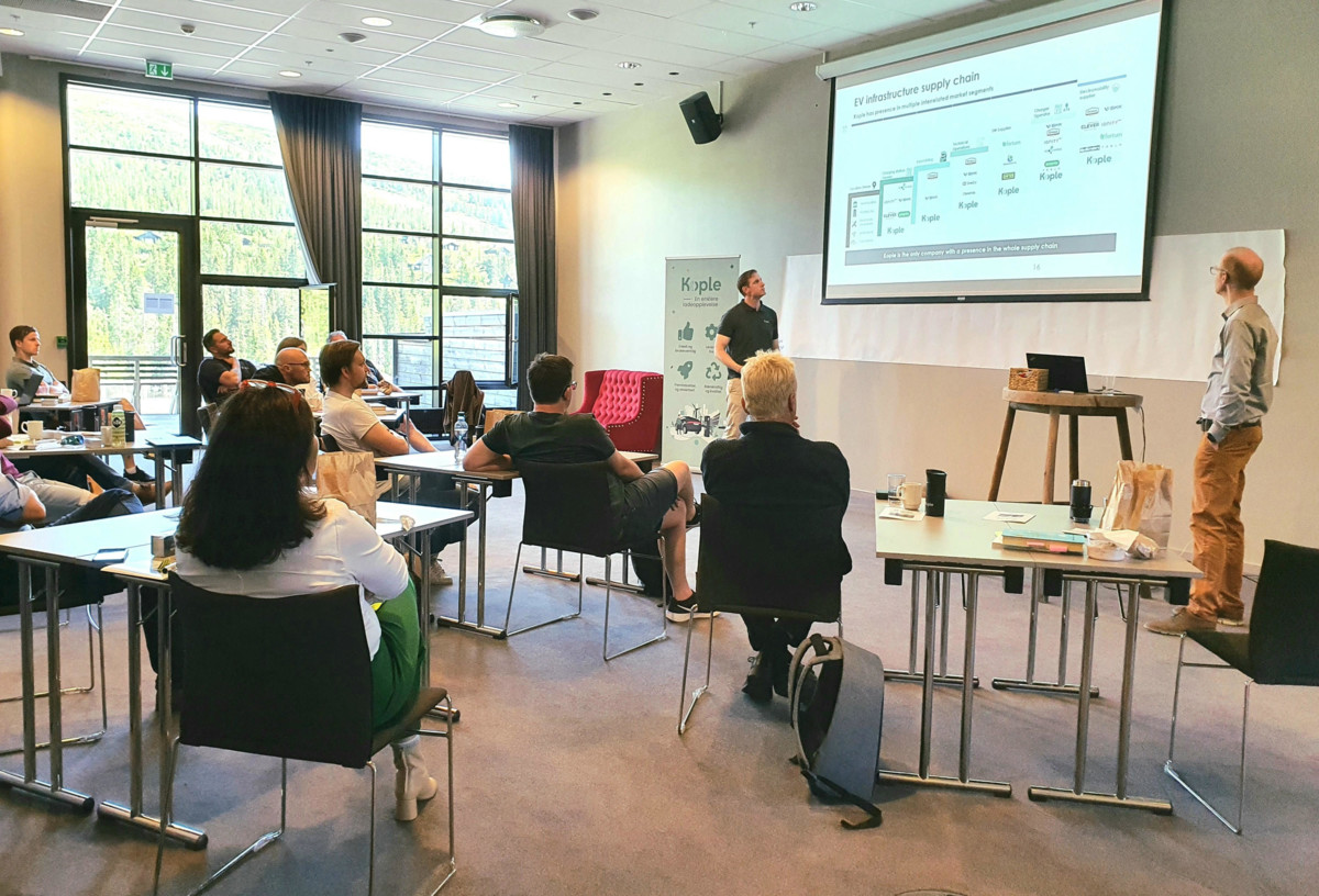 People observing a whiteboard in an educational environment, with a friendly atmosphere and a green view outside the window.